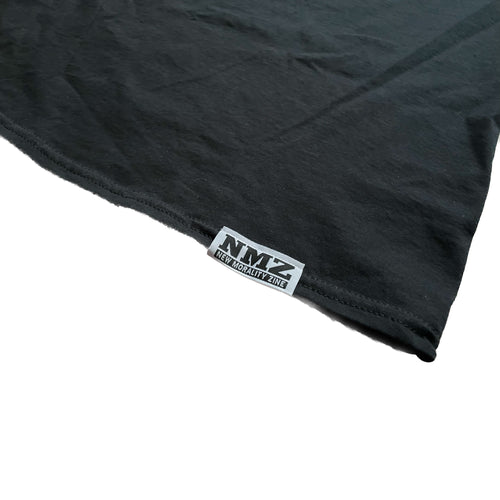 A close-up of the black NMZ "Tagged" Shirt shows its edge with a small sewn NMZ tag that displays NMYZ NEW MORALITY ZINE in black and white text.